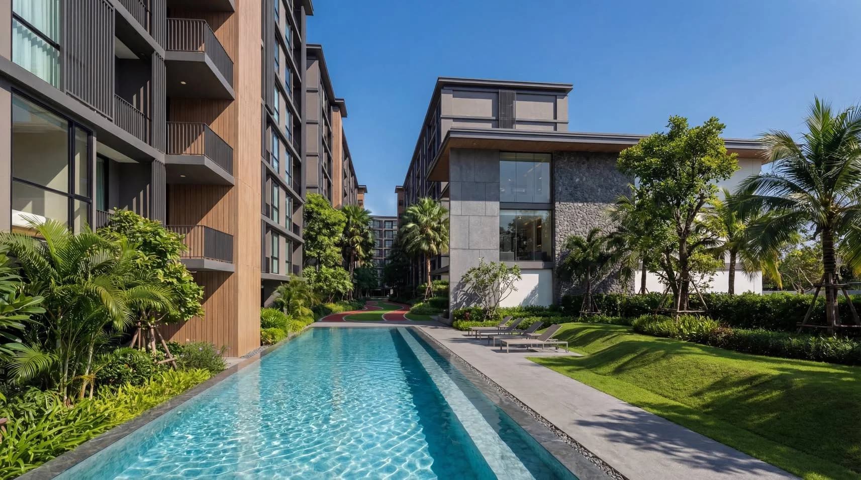 The half-Olympic lap pool with a lawn and loungers, the low-rise building at its end